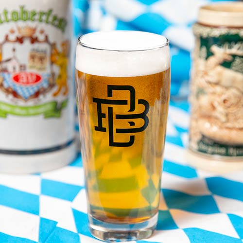 Dortmundar pale lager beer in a glass with 4-pack of cans