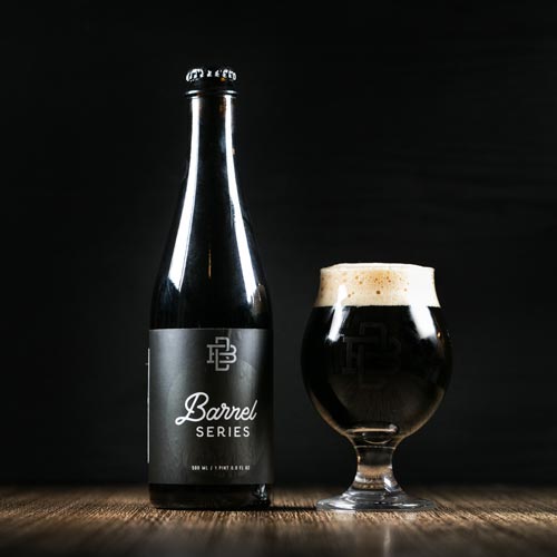 Barrel aged bottle with a beer glass