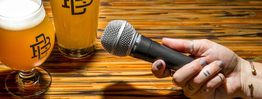 tattooed hand holding microphone next to two beers
